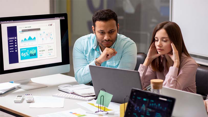 Two professionals analyzing data charts on computer screens – UI/UX design discussion at EdroxCode, India.