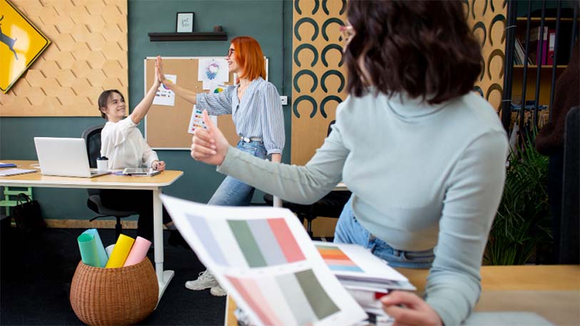 Two women collaborating in a creative workspace with color samples – representing enhanced user satisfaction through UI/UX design at EdroxCode, India.
